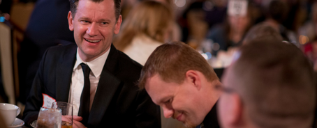 Men sitting around a table at a Remember America Speakers Series dinner